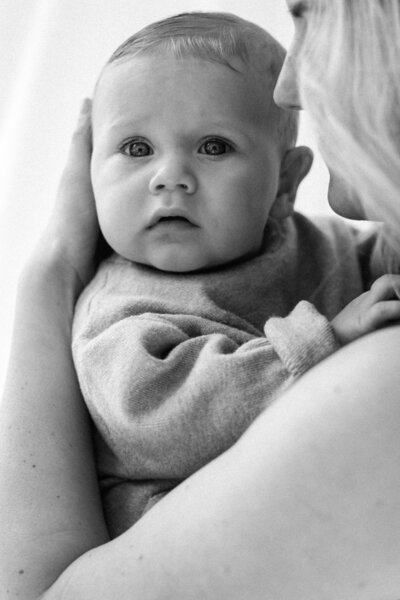 een vader en een moeder van een pasgeboren baby die trots naar elkaar kijken