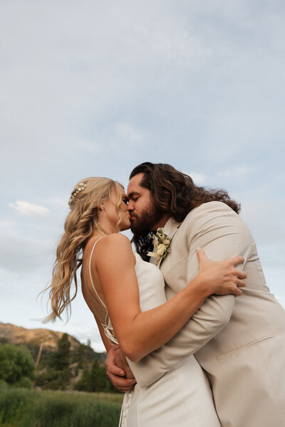 bride and groom kissing with mountains in the background