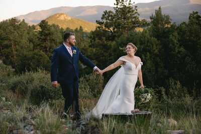 Bride and groom walk along mountainside during elopement day sunset.