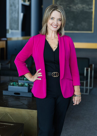 woman in professional outfit posing for headshot with hand on hip