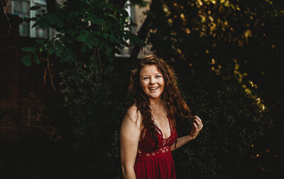 Maryland wedding photographer standing in a greenhouse in a red dress