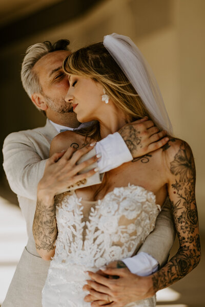 Femme enceinte de profil, assise dans l'eau dénudée, entourant sous ventre de ses bras et portant une couronne de fleurs lors d'un shooting photo.