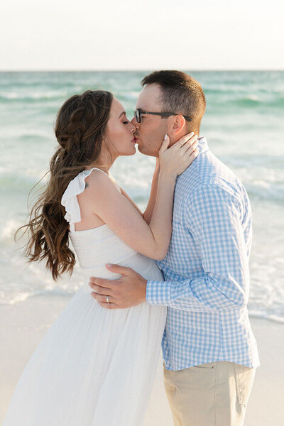 Expecting couple shares a kiss at the beach during a light and airy maternity session by Andrea Krey Photography