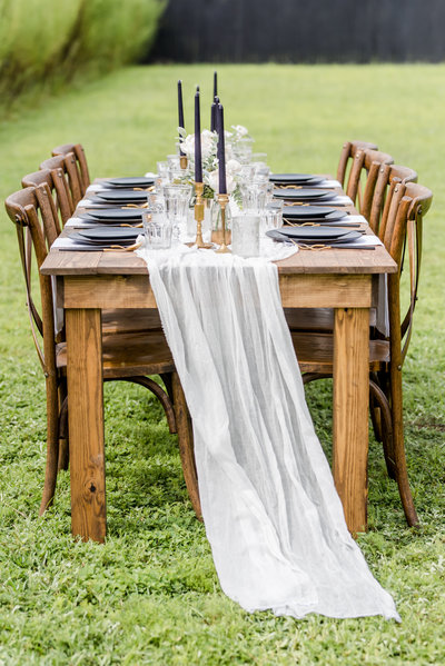 Farm table set for a wedding with white table runner, place settings and candles