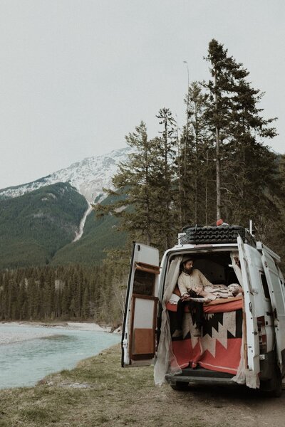 Couple cuddling in van on creek bed in Canada