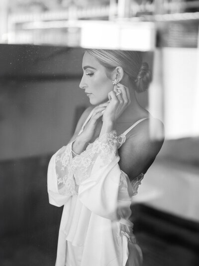Fine art wedding photography capturing an intimate bridal moment as the bride puts on earrings before her Arizona wedding ceremony.
