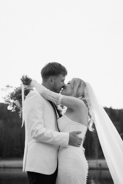 bride and groom wrapped in a loving embrace with snowy Banff mountains in the background, captured during an intimate destination wedding