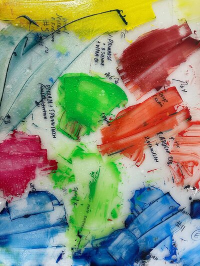 A mixing palette covered with labeled swatches in primary and secondary colors—showing detailed notes for ink color matching.