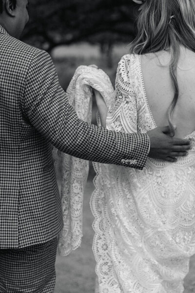 Black-and-white photograph of a bride and groom walking together on their wedding day in Colorado
