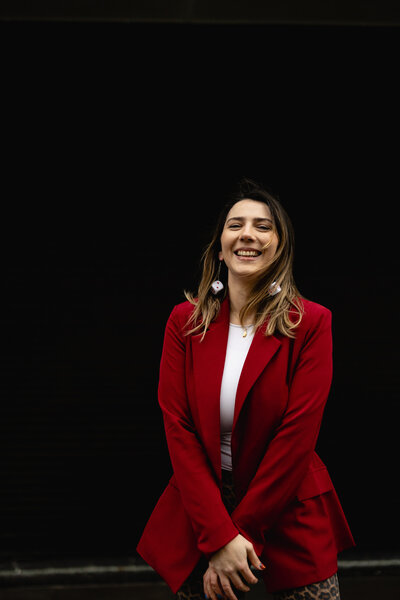 Emma, an Irish wedding planner & stylist, smiling in a red blazer and leopard pants 