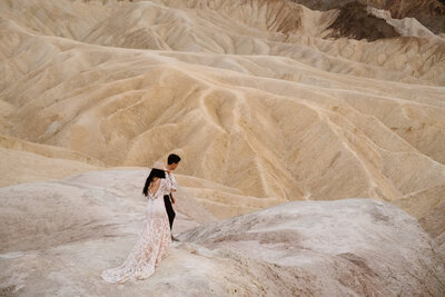 Couple looking at one another while holding a lantern overlooking a canyon valley