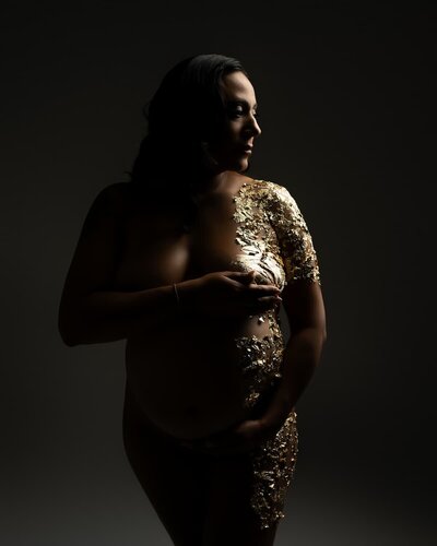 Dramatic maternity photo featuring gold leaf foil and moody lighting – Hello Photography studio in Austin, Texas
