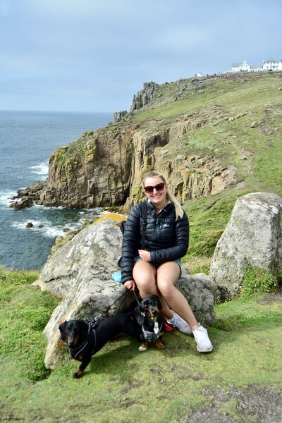 Amy on a cliff overlooking the sea with her two dogs