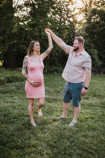 Expecting mom and dad dancing in garden while wearing pink and blue in Baltimore Maryland.