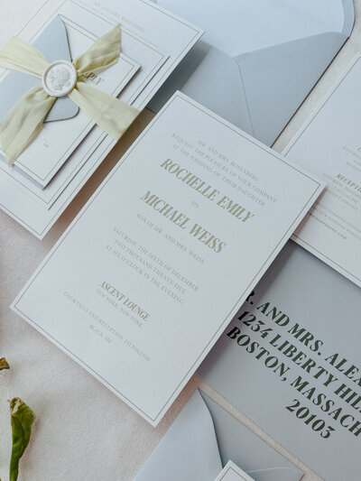Orange, lemons, orange flowers, monarch butterflies in a woven basket with a Save the Date card and RSVP card present.