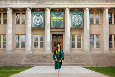 Colorado State University graduate walking towards the camera during her graduation photo session at The Oval in Fort Collins, Colorado.