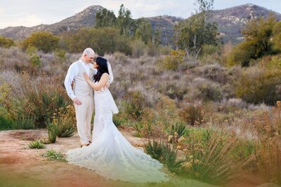 Wedding couple posing for portrait in field with mountain view in Fallbrook California