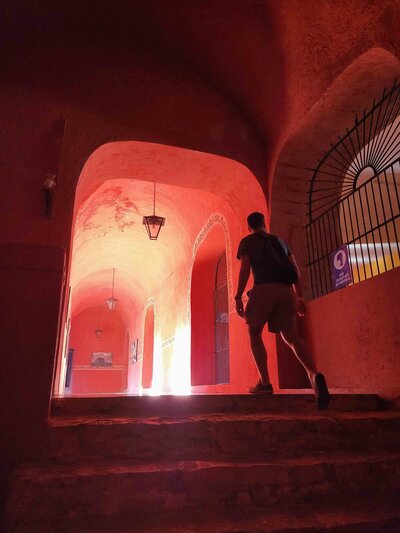 Sunlight streaming through the arched passageways of a red-walled monastery in Valladolid, Yucatán ©Stephanie Dosch | theViatrix Personalized Mexico Travel Planning