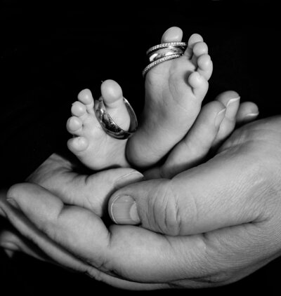newborn with wedding rings on his feet