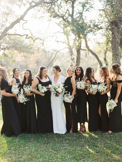 Bride standing with her bridesmaids in black dresses