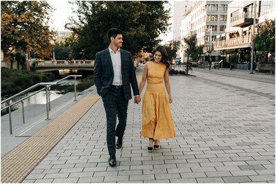 couple engaged walking city cbd christchurch photographer wedding suit yellow dress holding hands
