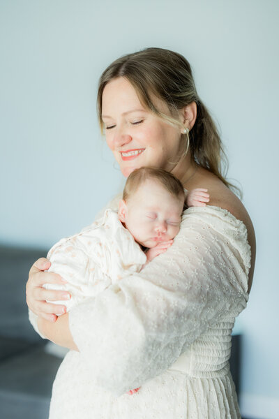 baby with bow on her head smiling at camera in-home Tampa newborn photography session.