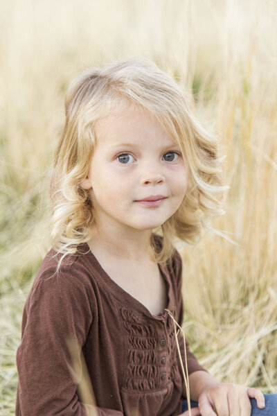 Beautiful blonde toddler girl in a field of tall fall grass