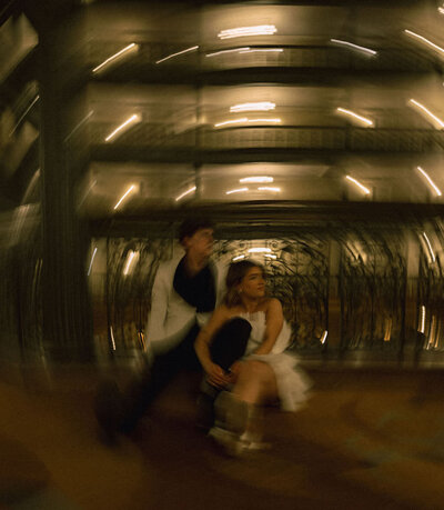 A wedding couple sitting together with lights blurred around them.