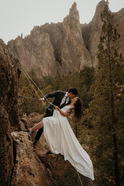 Bride and groom go rock climbing in their wedding attire during their Oregon elopement photography session