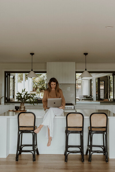 Lady siting on kitchen bench on laptop