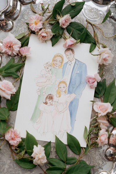 Watercolour family portrait surrounded by pink roses and greenery on an ornate silver tray.