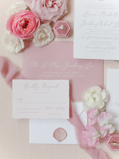 Pink wedding invitations surrounded by white and pink flowers