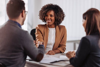 Professional woman shaking hands with male interviewer while female interviewer is smiling at the woman