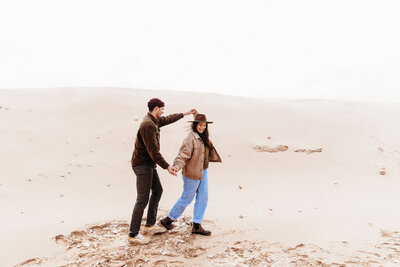 man and woman walking on sand dunes