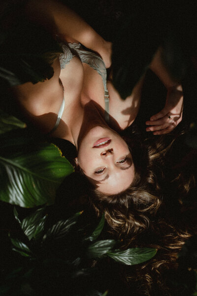 portrait of a brunette in a bralette surrounded by plants