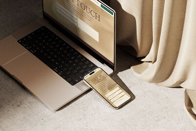 A laptop and phone on a table beside a curtain, symbolizing therapist branding and website design.