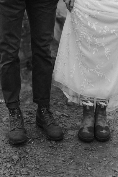 Close-up of the couple’s hiking boots resting on a mountaintop trail during their adventurous Virginia elopement, captured in a candid, editorial style.
