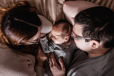 Mom and dad snuggling on bed at in-home newborn session in concord NH by lisa smith photography