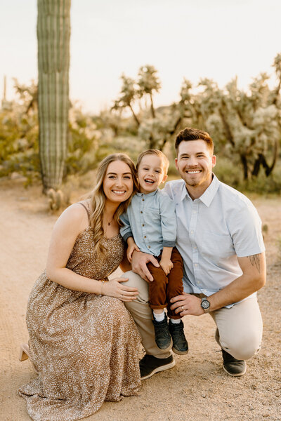 parents kneel with son in arizona landscape