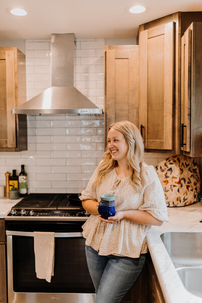 Kenna in her kitchen smiling as she leans against the counter