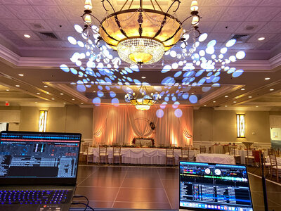Elegant ballroom with custom lighting effects on the ceiling, DJ booth, and AV production equipment set up for a wedding reception.