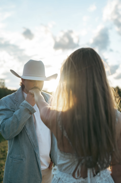 Golden-hour couple’s session in a Nashville, TN field—cowboy hat, soft light, and romantic energy captured in a dreamy, film-inspired style.