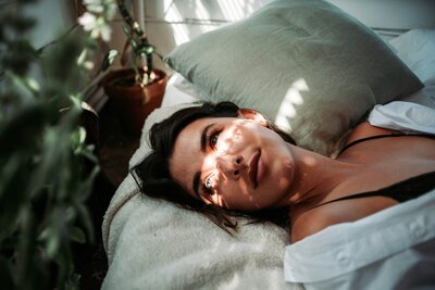 Woman laying in early sun light in bed