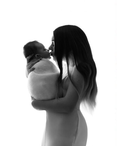 black and white photo of mom and baby kissing with baby wrapped near dupont