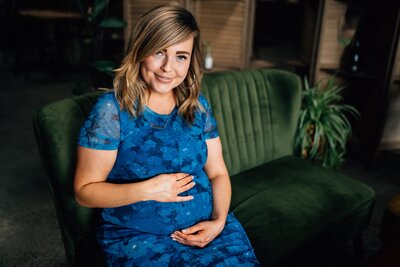 Pregnant lady in blue dress smiling at camera, sitting on green couch inside Northside Wines, Northcote.