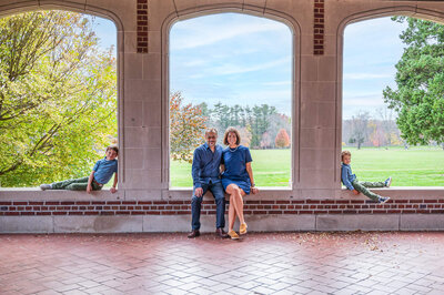 Connecticut family with their two toddler sons, sitting in arched openings at Waveny Park in New Canaan, CT.