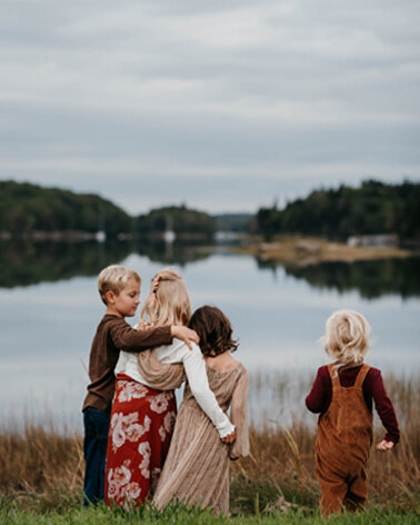 Family Photographer, four siblings standing next to lake