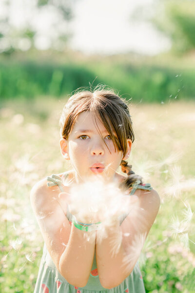 young girl blowing dandelion seeds in her Chicago family photos