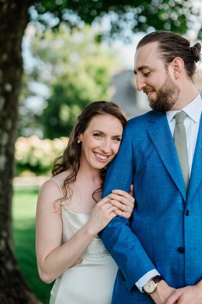 A groom looking down at his bride as she smiles and hangs onto his arm