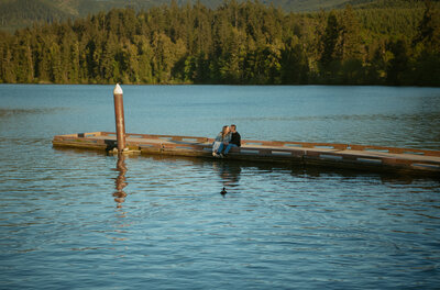 Couple sitting by the lake with a duck swimming to them